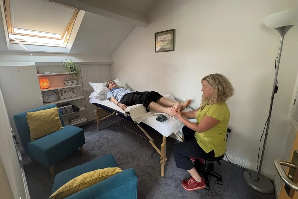 The practice room with a reflexology couch and teal armchairs